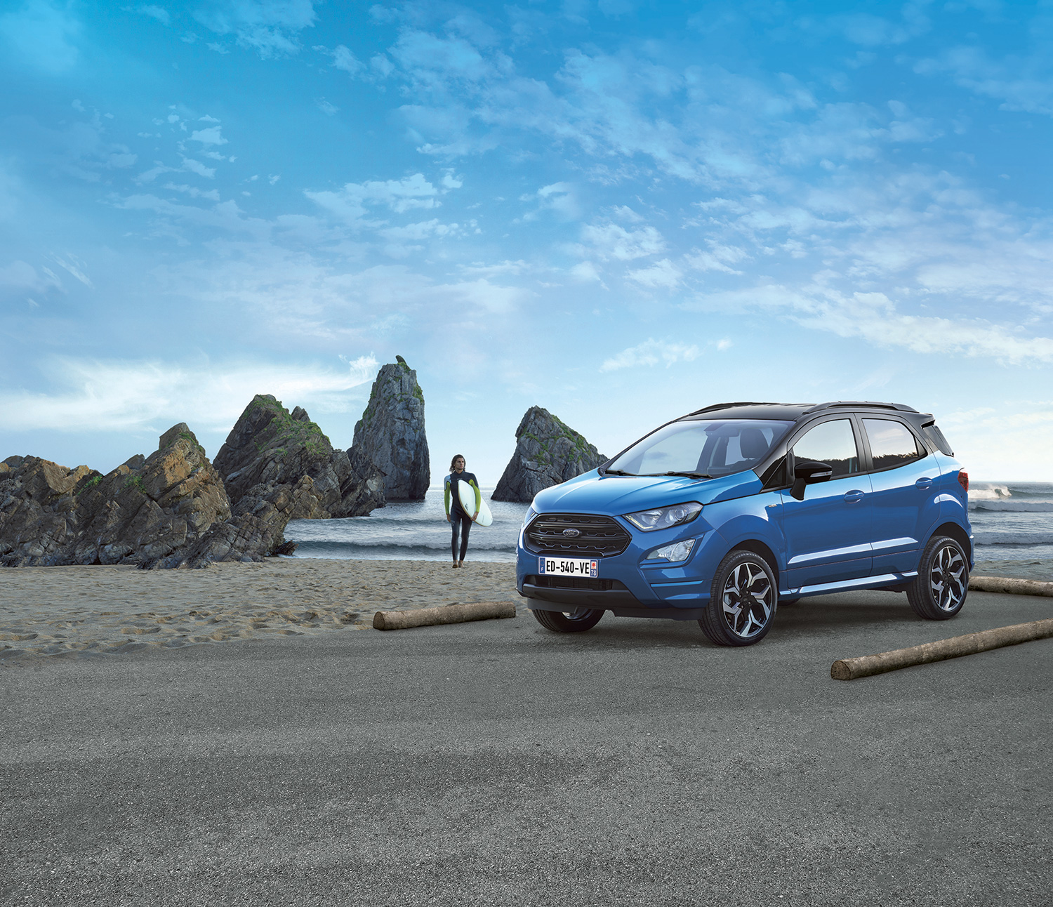 Publicité Ford - montre un surfeur à côté d'une ford bleue avec en paysage la mer et des rochers